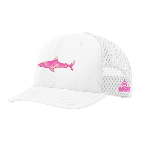 White cap with pink shark design on a sandy beach